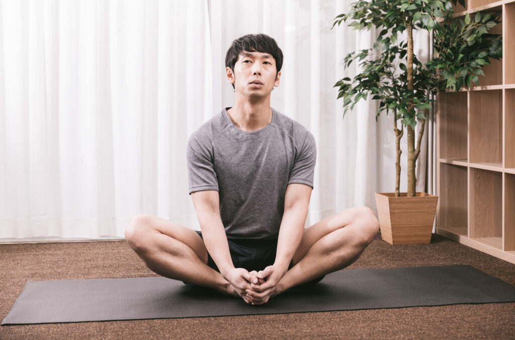 ヨガマットのうえでストレッチしながら考え中の人
